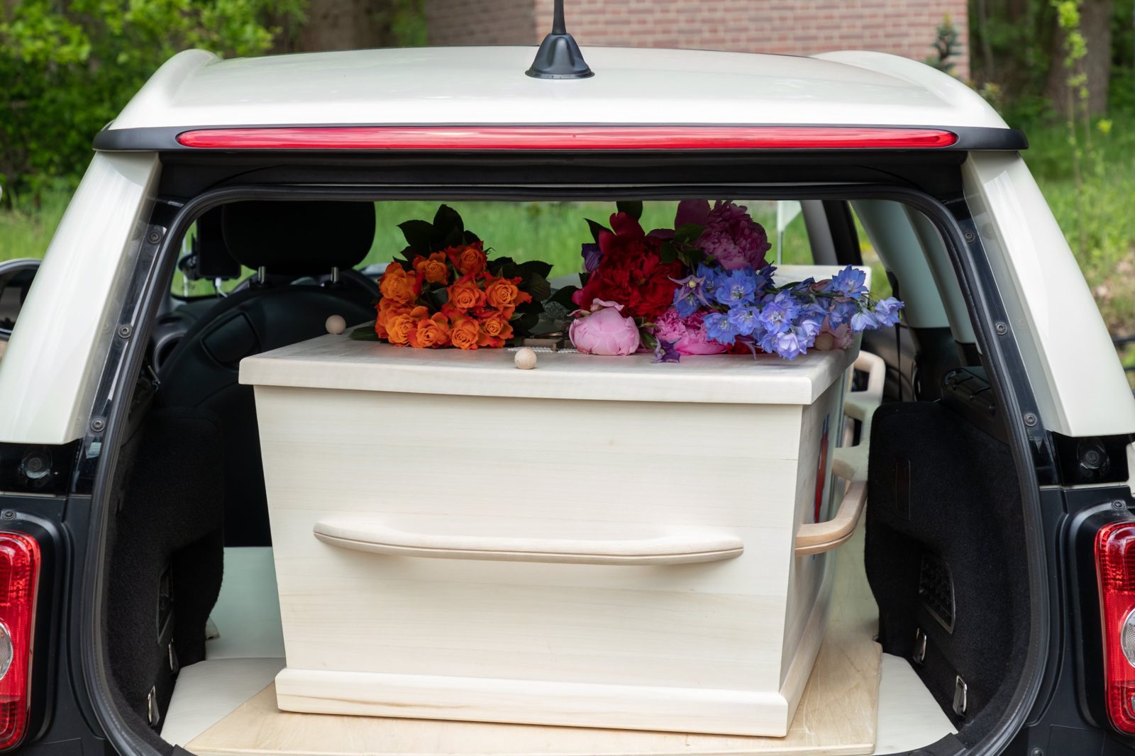 Een lichte houten kist met losse bloemen in de Minirouwauto