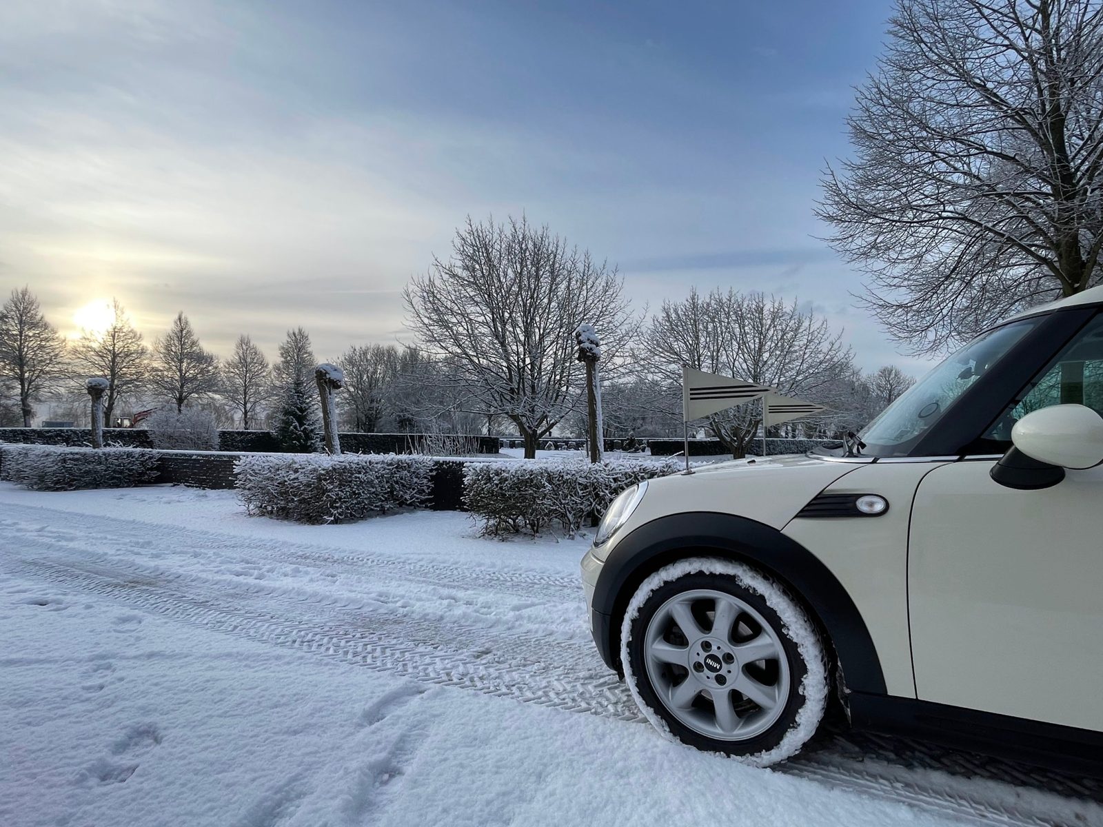 De voorkant van de Minirouwauto met vlaggetjes in de sneeuw